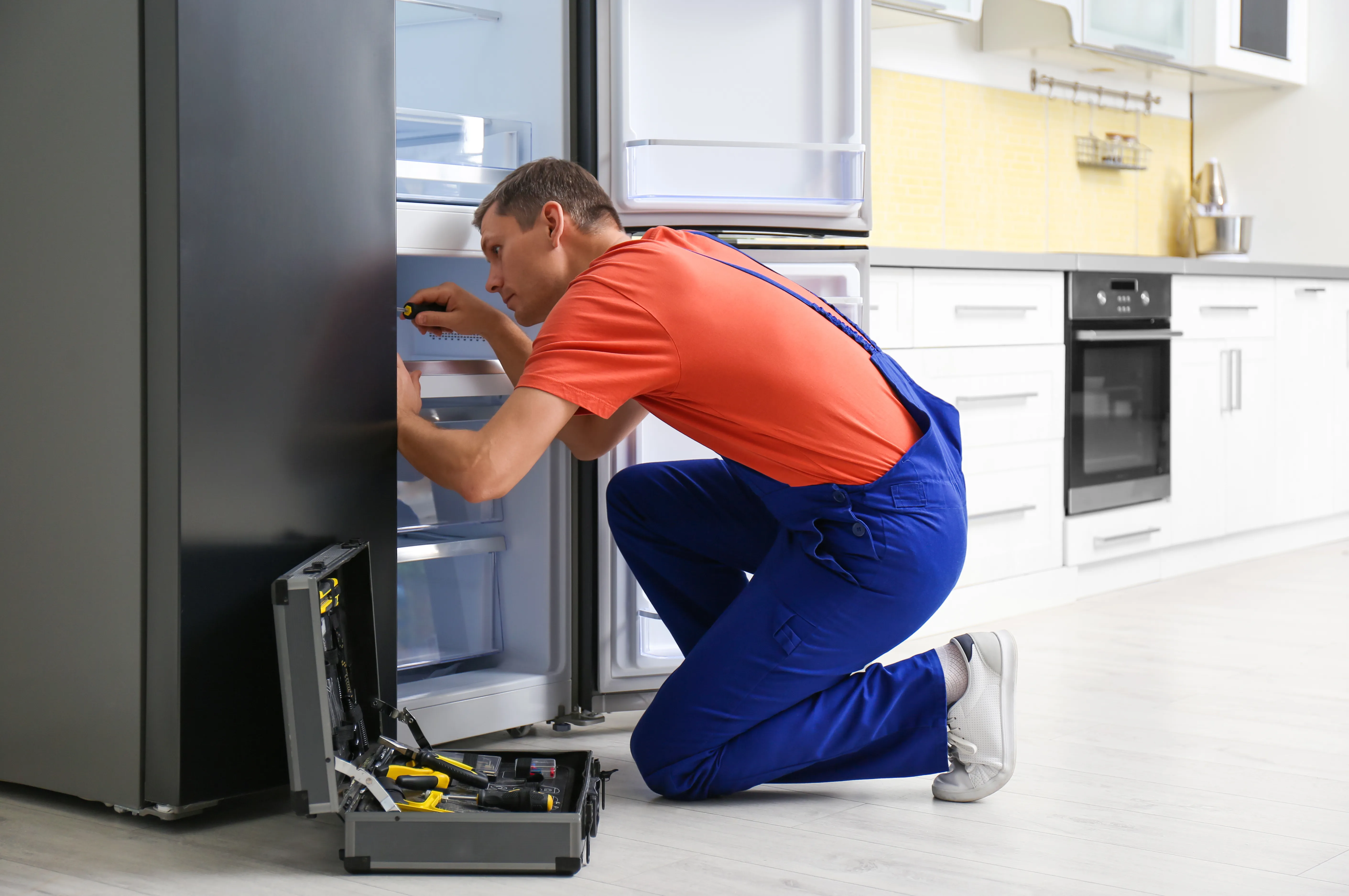 Refrigerator Repair vs. Replace Guide: Making the Right Decision for Jeddah Homes Technician repairing a household refrigerator